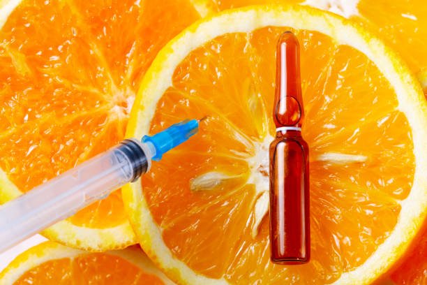 Vitamin c, natural anti aging cosmetics serum and syringe over orange fruits