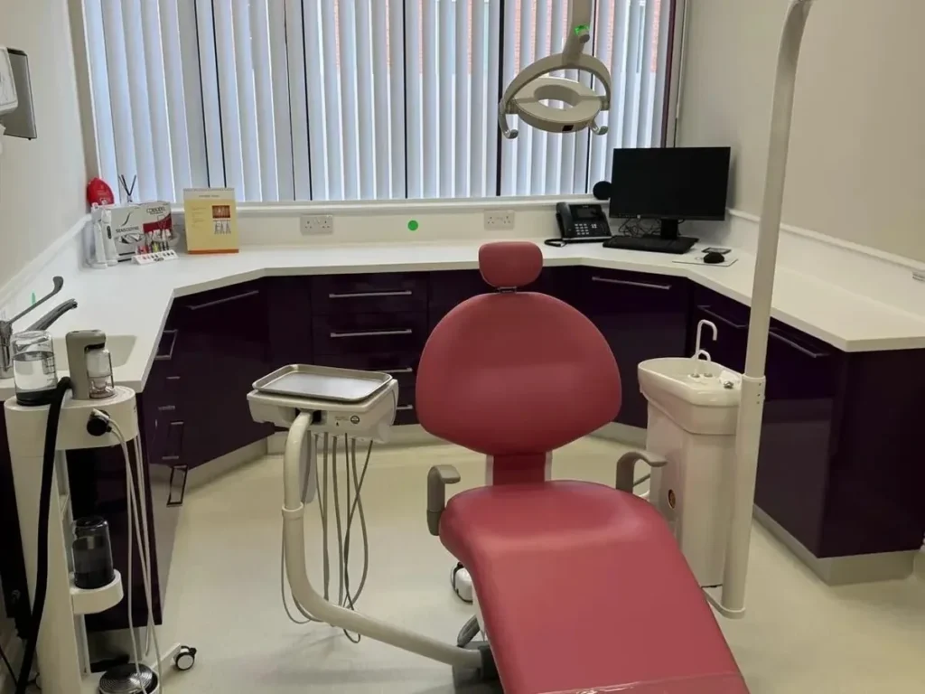 Dental hygiene surgery at Rectory Dental Clinic featuring a pink dental chair, overhead examination light, computer workstation, and modern hygiene treatment equipment.