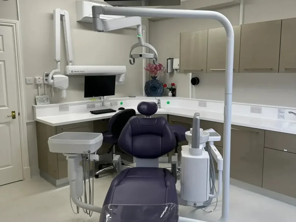 Dr. Alfie Chang’s modern dental surgery room at Rectory Dental Clinic with a dental chair, overhead examination light, digital monitor, and integrated treatment equipment.
